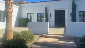 Un edificio moderno con techo plano, ventanas grandes y una puerta marcada con el número 3076.