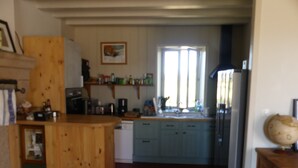 Una cocina con armarios de madera, lavavajillas, un lavabo y una ventana con persianas.
