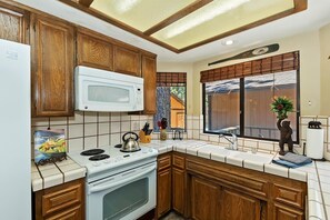 Una cocina con armarios de madera, una estufa blanca y un microondas.