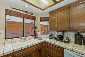 Una cocina con armarios de madera, una ventana con persianas, un lavamanos, un tostador y una cafetera.