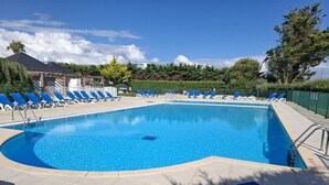 En swimmingpool med blå stolar och en klar himmel.