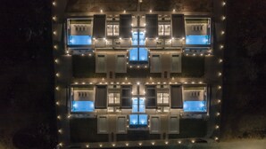 Ein Gebäude mit einer symmetrischen Fassade, das mehrere Fenster und Türen aufweist und von Lichterketten beleuchtet wird.