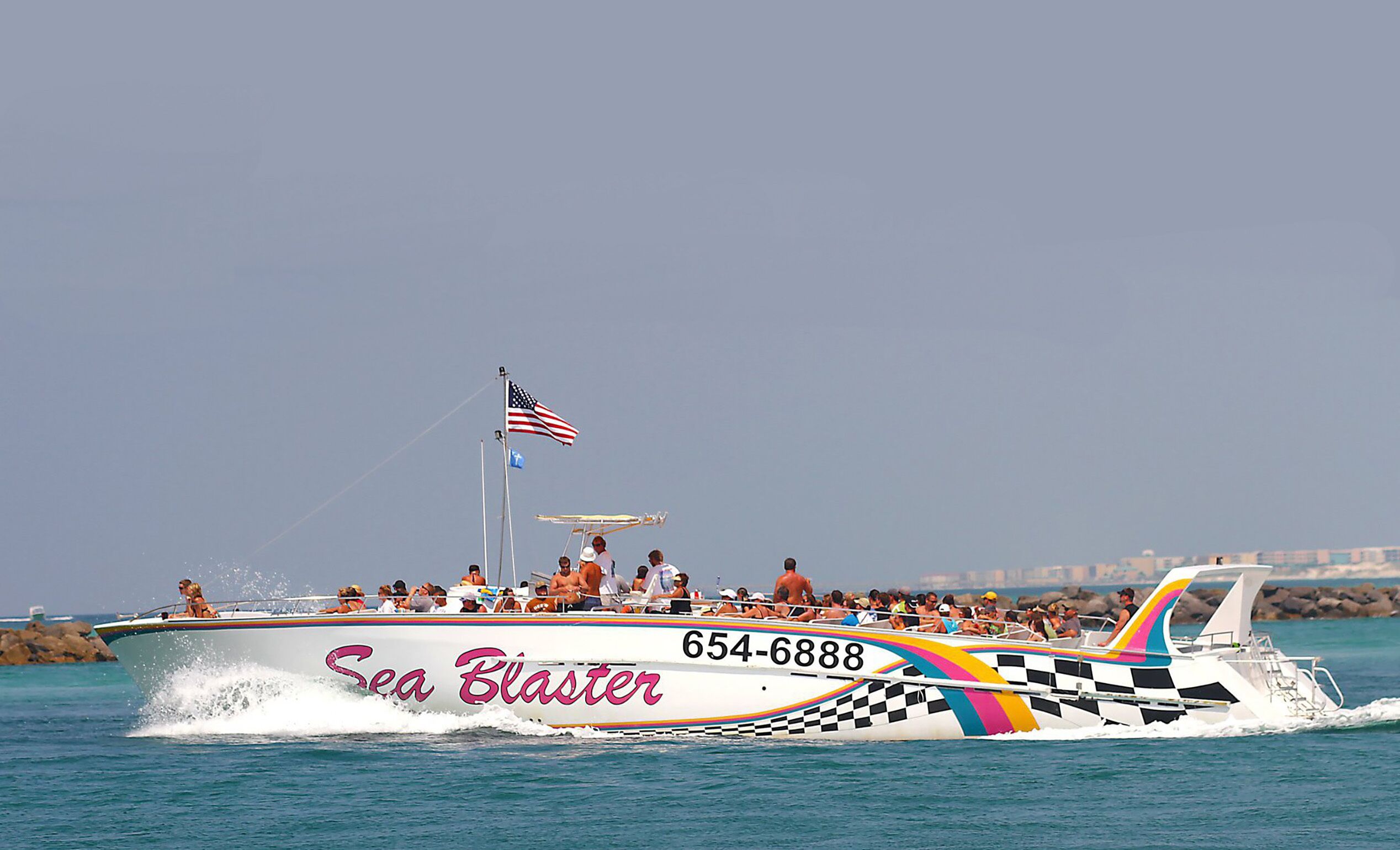 Un barco llamado 'Sea Blaster' con el número 654-6888, transportando pasajeros.