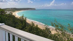A coastal view with a beach, ocean, and a distant hill with buildings. - Le Caprice – Iconic Clifftop Estate Above Baie Rouge, Terres Basses (Lowlands)