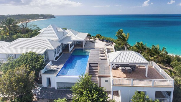 A resort with a swimming pool, multiple decks, and a view of the ocean. - Le Caprice – Iconic Clifftop Estate Above Baie Rouge, Terres Basses (Lowlands)