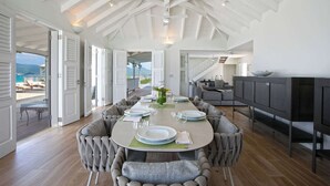 A spacious dining area with a high ceiling and open doors leading to a balcony with a view of the sea. - Le Caprice – Iconic Clifftop Estate Above Baie Rouge, Terres Basses (Lowlands)