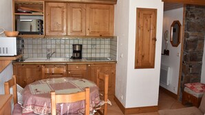 A compact kitchen with wooden cabinets, a microwave, a coffee maker, and a sink.