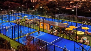 A multi-level tennis court complex with seating areas and a small building, surrounded by a fence and overlooking a residential area. - Cap Esterel le village T2 Garden level-CLIM-Sea view-Pool and parking included (Saint-Raphaël)