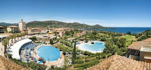 Un resort con diverse piscine, un cortile centrale e vista sul mare e sulle montagne.