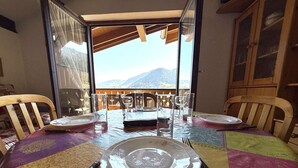 A dining table set for four with a mountain view through a glass door.