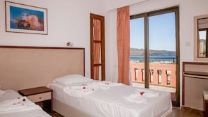 A hotel room with a bed, a nightstand, a window with a view of the sea, and a painting on the wall. - Ekavi Apartments (Chania)