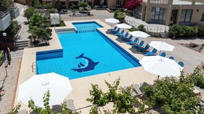 A swimming pool with a dolphin design, surrounded by lounge chairs and umbrellas. - Ekavi Apartments (Chania)