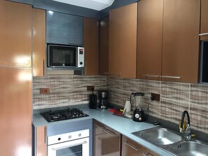 Uma cozinha moderna com eletrodomésticos de aço inoxidável, micro-ondas, cafeteira e pia.
