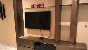 Een moderne entertainmentkast met een flatscreen televisie, een glazen plank en een kastje eronder.