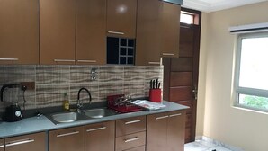 Een moderne keuken met bruine kastjes, een granieten aanrecht, een ingebouwde oven en een raam dat natuurlijk licht binnenlaat.