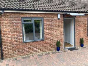 A brick building with a tiled roof, a large window, and a door leading to a covered entrance. - Spacious Annex 2 Miles From Coast (Holt)