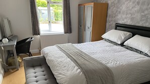 Une chambre à coucher avec un lit, une table de chevet et un banc recouvert d’un tissu gris.