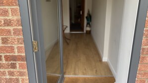 Un couloir avec un mur en briques d’un côté et une porte en verre de l’autre.