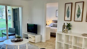 A modern living room with a flat-screen TV, a dining table, and a large window. - 350A - Boca Retreat w/ Pool, Parking, Near Evert Tennis & Shops (Boca Raton)