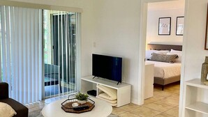A modern living room with a flat-screen TV, a coffee table with a tray, and a sofa. - 350A - Boca Retreat w/ Pool, Parking, Near Evert Tennis & Shops (Boca Raton)