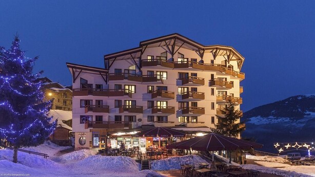 A multi-story hotel with balconies, outdoor seating, and a snow-covered landscape. - Courchevel La Tania, 2-room apartment with basement parking (Courchevel)