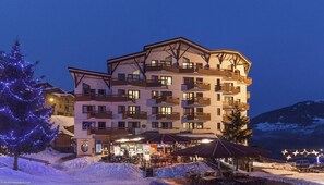 A multi-story hotel with balconies, outdoor seating, and a snow-covered landscape. - Courchevel La Tania, 2-room apartment with basement parking (Courchevel)