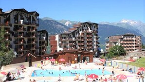 A hotel with multiple balconies overlooking a pool area, surrounded by mountains. - Courchevel La Tania, 2-room apartment with basement parking (Courchevel)