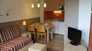 A compact living space with a sofa, dining table, chairs, a television, and a kitchenette. - Courchevel La Tania, 2-room apartment with basement parking (Courchevel)