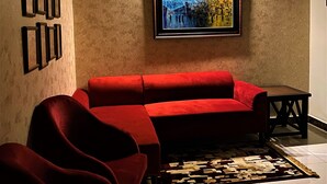 Una sala de estar moderna con un sofá rojo, un cuadro enmarcado y suelo de baldosas.