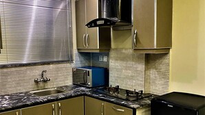 Una cocina compacta con microondas integrado, estufa a gas y refrigerador negro.