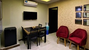 Un comedor con una mesa y sillas, un televisor de pantalla plana en la pared y un sofá rojo.