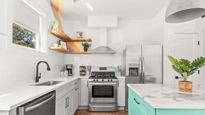 A modern kitchen with white cabinetry, a stainless steel stove, and a teal countertop. - The Jolene • Bubbly Bar w/ Views • 5min to DT! 🍾 (Nashville)