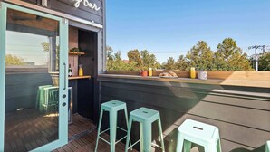 An outdoor seating area with a bar named 'Bubble Bar', featuring two stools and a wooden counter with a glass enclosure. - The Jolene • Bubbly Bar w/ Views • 5min to DT! 🍾 (Nashville)