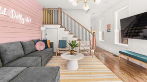 Un salon moderne avec un canapé gris, une table basse ronde et un escalier doté de rampes en bois.