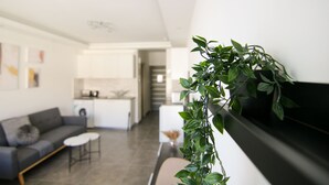 A modern living room with a sofa, coffee table, and a potted plant. - Phaedrus Living Seaside Flat Athina 116 (Paphos)