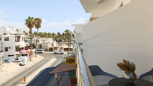 A balcony with a clear view of a street, palm trees, and a sign for 'EVANS'. - Phaedrus Living Seaside Flat Athina 116 (Paphos)