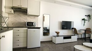 A modern kitchen with white cabinets, a built-in microwave, and a compact refrigerator. - Phaedrus Living Seaside Flat Athina 116 (Paphos)