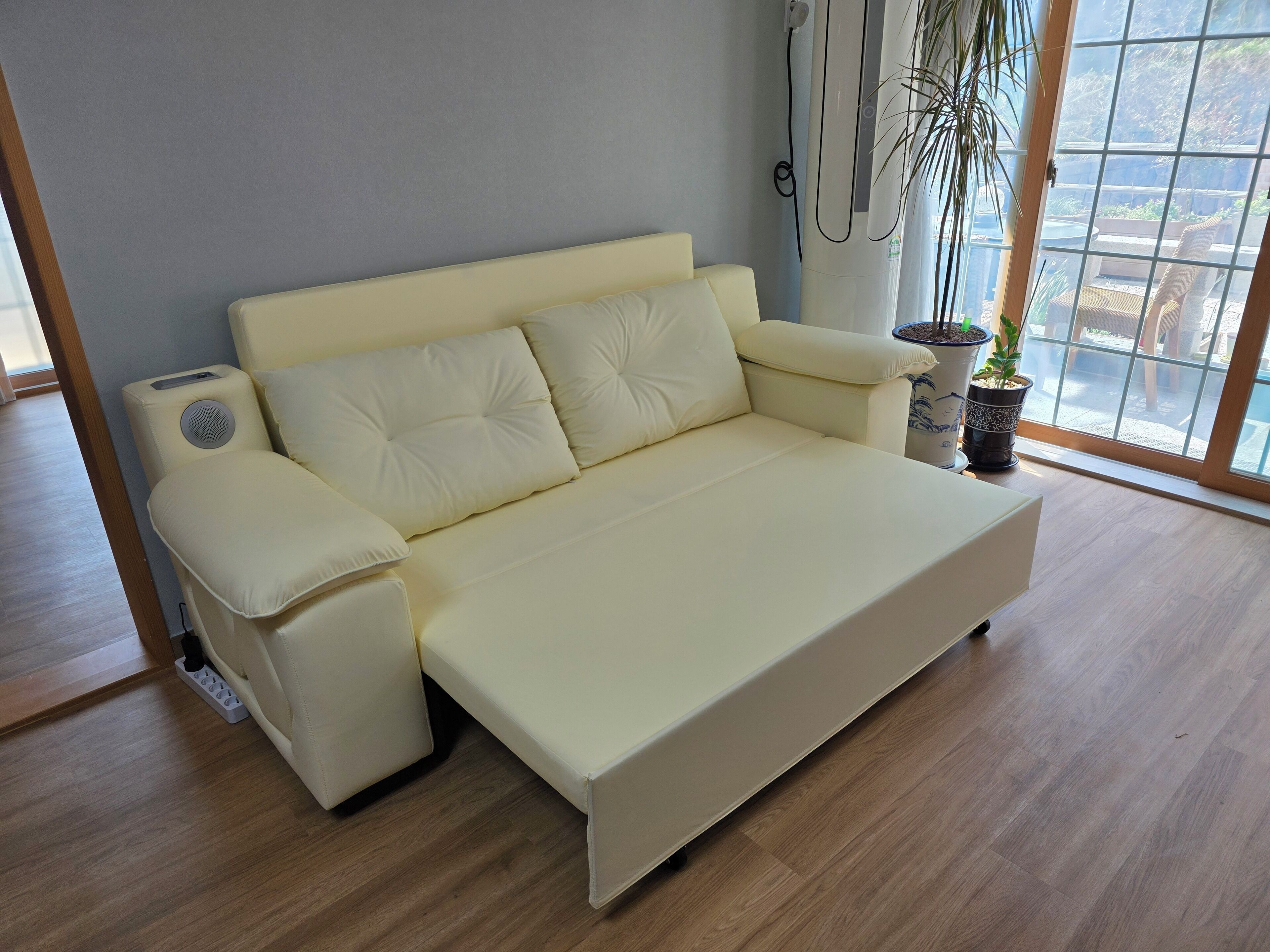 En moderne stue med en beige sofa, et lille sofabord og en potteplante.