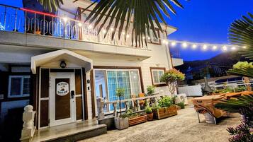 A two-story building with a balcony, outdoor seating area, and potted plants.