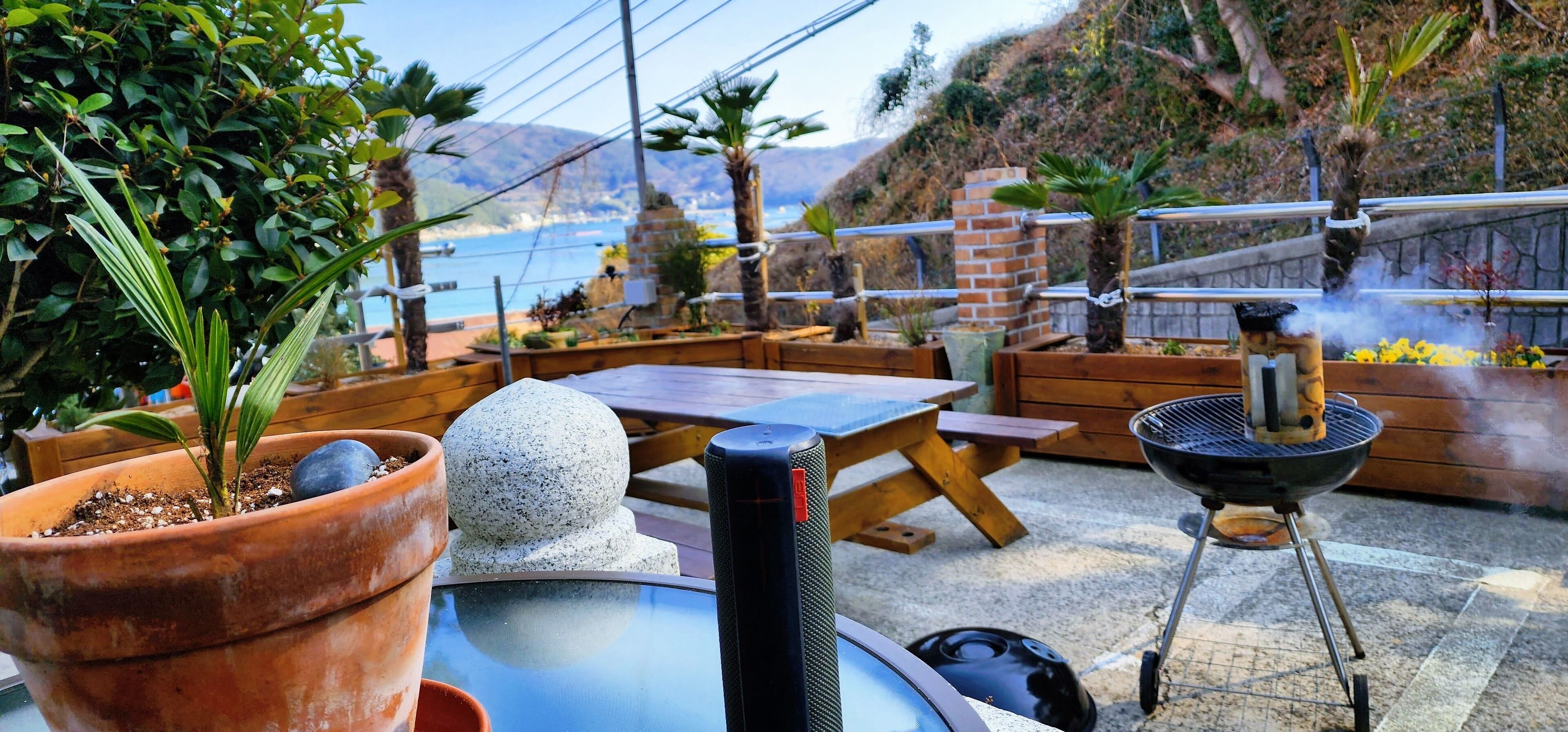An outdoor patio with a table, chairs, a grill, and potted plants.