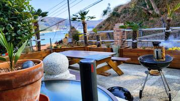 An outdoor patio with a table, chairs, a grill, and potted plants.