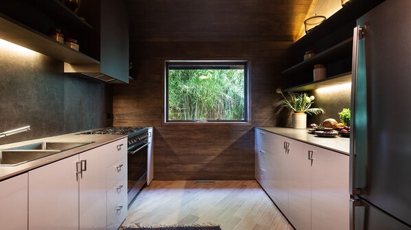 Una cocina moderna con una isla central, horno integrado y ventana con vistas a la vegetación.
