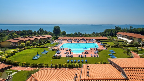 Ein Resort mit Schwimmbad, Liegestühlen und Meerblick.
