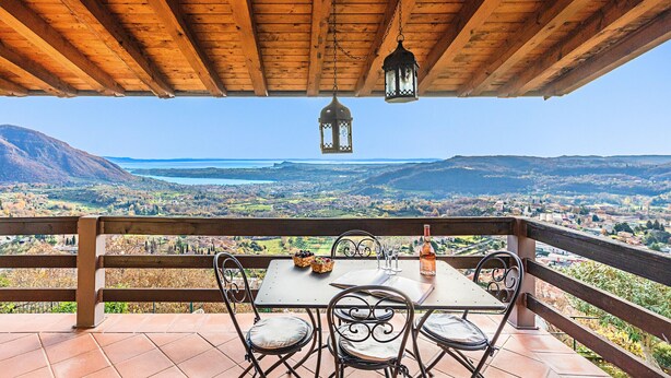 A wooden pergola with a table and chairs overlooking a scenic landscape.