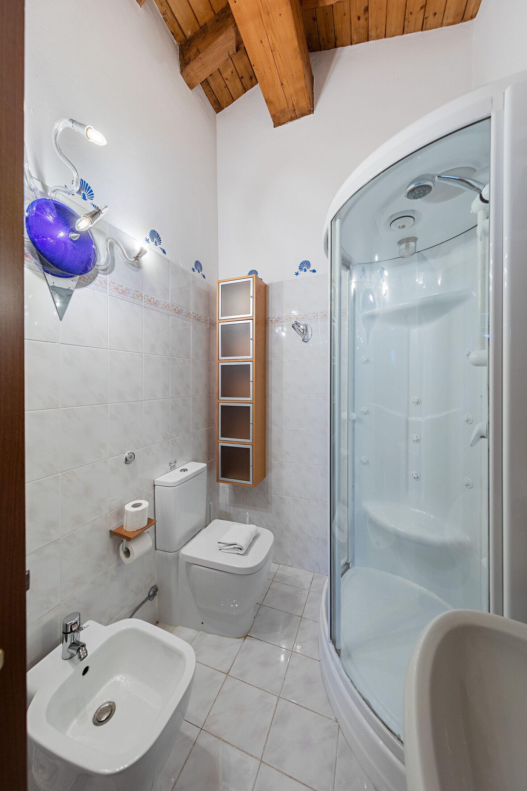 A modern bathroom with a glass-enclosed shower, a white sink, and a toilet.