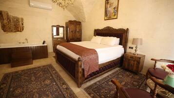Un dormitorio con una cama grande, un aparador de madera, un tocador con espejo, una araña y un cuadro en la pared.