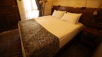 Una cama con una colcha estampada, un cabecero de madera y dos almohadas blancas.