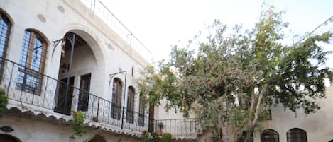 Un patio con fuente, mesas al aire libre y un árbol.