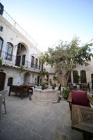 Un patio con fuente, mesas al aire libre y un árbol.