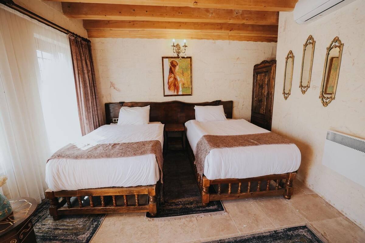 A room with two wooden beds, a painting on the wall, and a radiator.